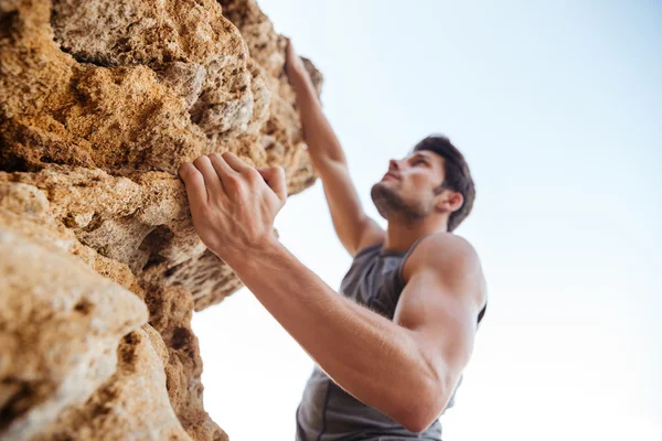 Jovem escalando parede rochosa natural — Fotografia de Stock