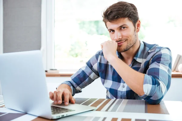 Hombre serio en camisa a cuadros trabajando con el ordenador portátil en casa —  Fotos de Stock