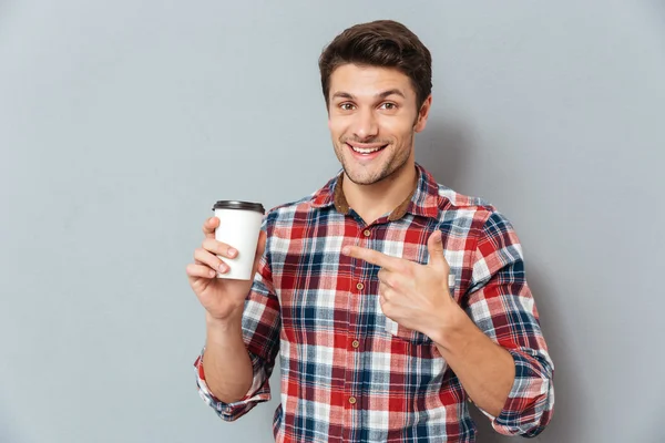 Jonge knappe Glimlachende man wijzende vinger op afhaalmaaltijden koffiekopje — Stockfoto