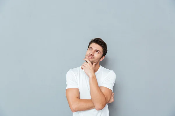 Pensivo atraente jovem sorrindo e pensando — Fotografia de Stock