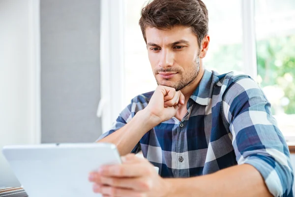 Jovem pensativo pensando e usando tablet em casa — Fotografia de Stock