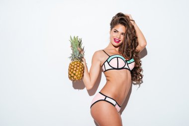 Young smiling pretty sexy girl holding pineapple and posing