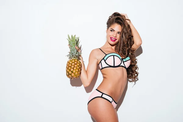 Young smiling pretty sexy girl holding pineapple and posing — Stok fotoğraf