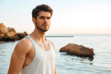 Genç yakışıklı adam atlet kayalık deniz kenarında ayakta