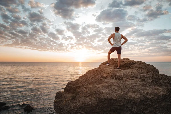 Jovem desportista de pé na rocha da montanha junto ao mar — Fotografia de Stock