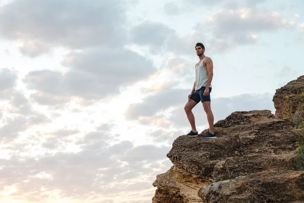 Casual νεαρός στέκεται πάνω στο βράχο του βουνού — Φωτογραφία Αρχείου