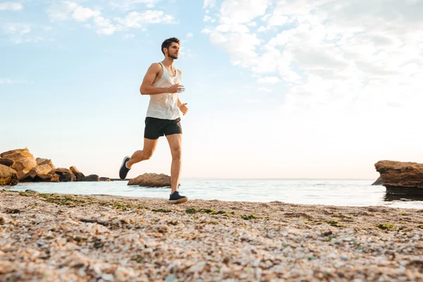 Handsome man athlete running at the beach — Stock Photo, Image