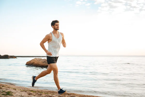 Handsome man athlete running at the beach — Stock Photo, Image