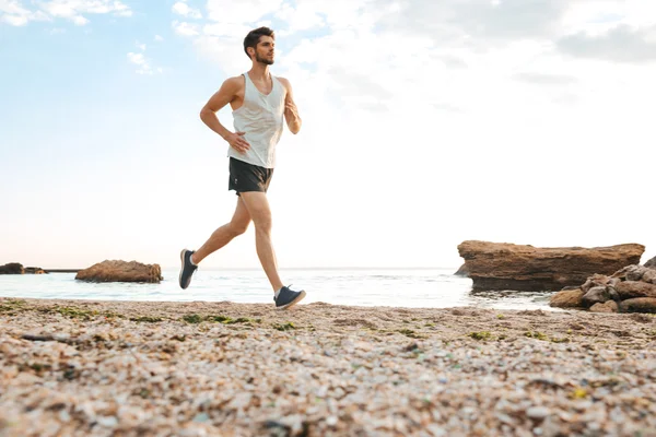 Hombre guapo atleta corriendo en la playa —  Fotos de Stock