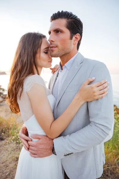 Pareja casada romántica de pie en la playa — Foto de Stock