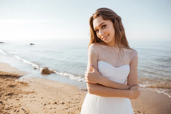 Junge schöne Frau im Hochzeitskleid am Strand — Stockfoto