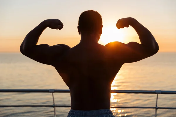 Silhuetten av muskulös visar biceps på sunnrise — Stockfoto