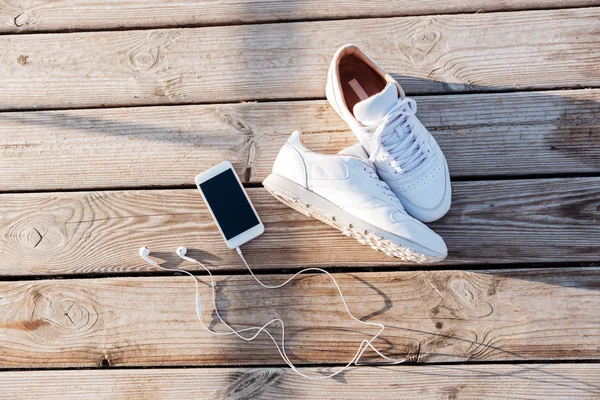 Sport concept - paio di sneakers bianche, smartphone e auricolari — Foto Stock
