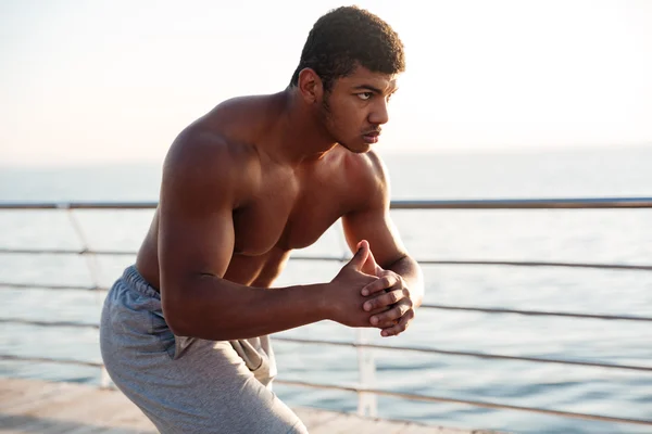 桟橋にスクワットをやって若いの上半身裸アフロ アメリカンのスポーツマン — ストック写真
