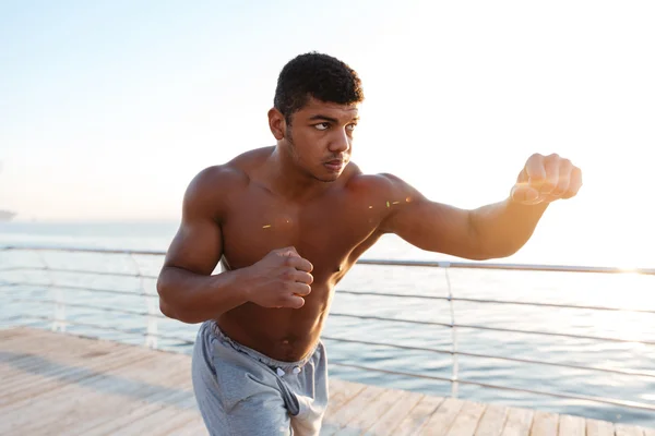 Joven deportista afroamericano haciendo ejercicios de boxeo en el muelle — Foto de Stock