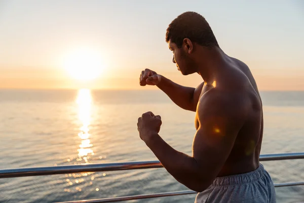 Handsome african man athlete working out on pier at sunrise