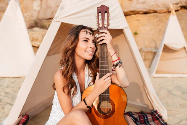 앉아서 해변에 wigwam에 기타를 들고 행복 한 여자 — 스톡 사진