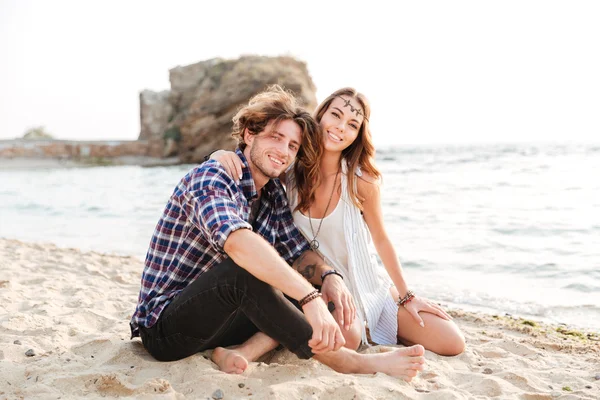 Jovem casal alegre sentado na praia — Fotografia de Stock