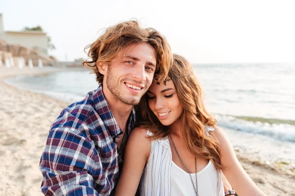 Пара сидящих и улыбающихся на пляже — стоковое фото