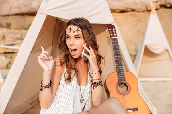 Amazed woman talking on cell phone in teepee at beach — Stock Photo, Image