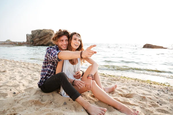 Sorrindo homem apontando o dedo para a praia com sua namorada — Fotografia de Stock