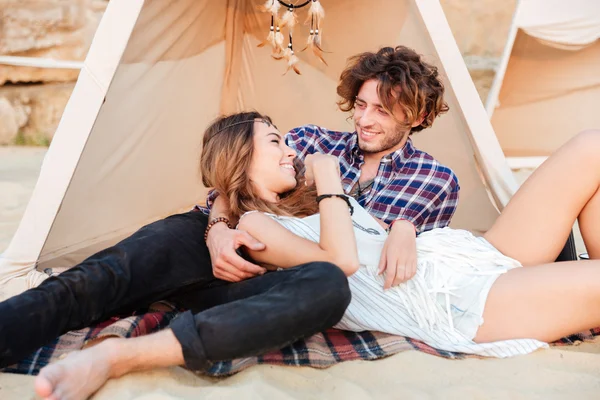 Pareja acostada y riendo en wigwam en la playa — Foto de Stock