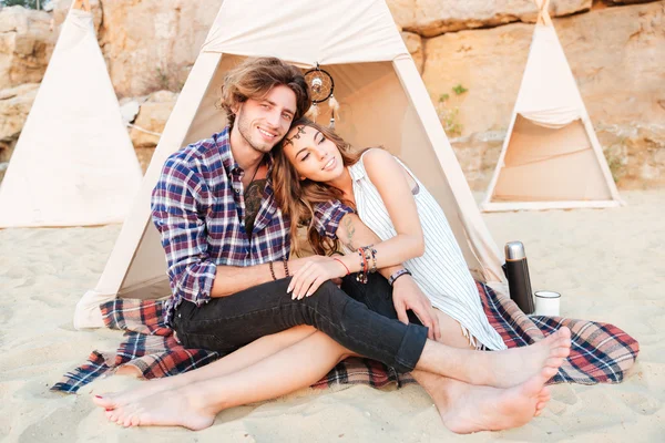 Pareja relajándose y abrazándose en wigwam en la playa — Foto de Stock