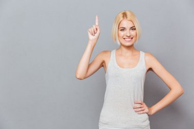 Smiling cute young woman pointing up clipart