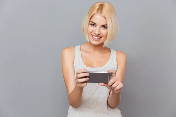 Portrait of happy charming young woman smiling and using smartphone — Stock Photo, Image