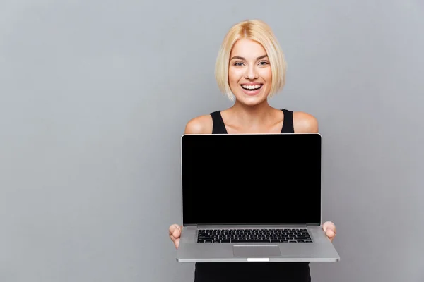 Feliz linda mujer joven sosteniendo la pantalla en blanco portátil — Foto de Stock