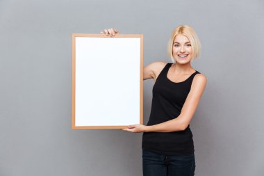Boş beyaz tahta tutan mutlu genç ve güzel kadın