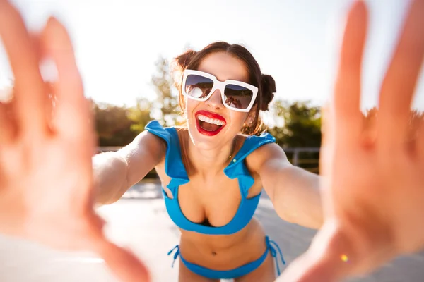 Jovem alegre em maiô azul e óculos de sol tomando selfie — Fotografia de Stock