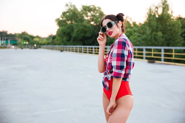 Brunette girl in sunglasses posing on the open road outdoors — Stock Photo, Image