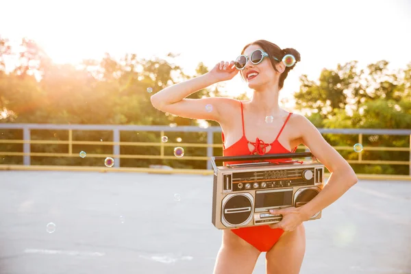 Дівчина в сонцезахисних окулярах і червоний купальник тримає старого рекордера — стокове фото