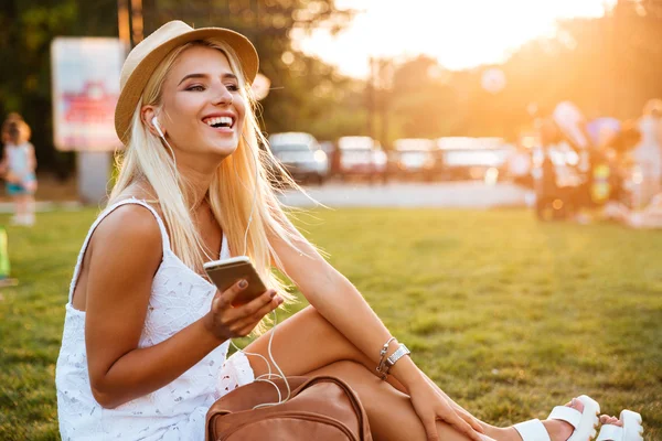 Lachende vrouw luisteren naar muziek tijdens de vergadering in park — Stockfoto