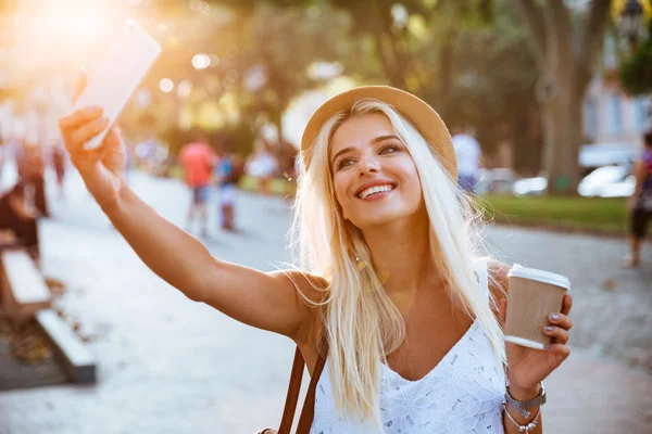 Młoda dziewczyna uśmiechający się podejmowania selfie stojąc na ulicy — Zdjęcie stockowe