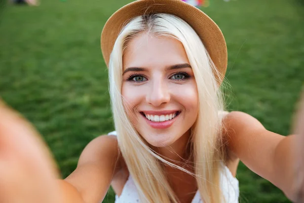 Молодая улыбающаяся веселая блондинка в шляпе делает селфи — стоковое фото