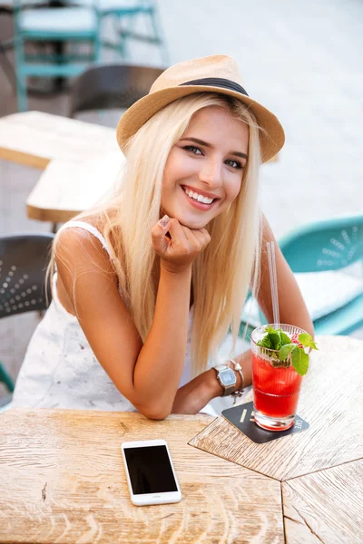 Happy woman with mobile phone drinking cocktail in outdoor cafe — Stock Photo, Image