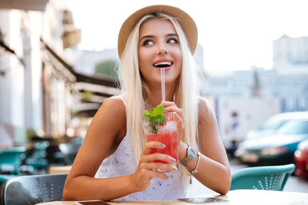 Beautiful young happy woman drinking cocktail while sitting in cafe — Stock Photo, Image