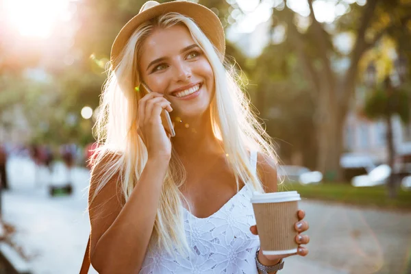 Chica sosteniendo llevar taza de café y hablar en el teléfono inteligente —  Fotos de Stock