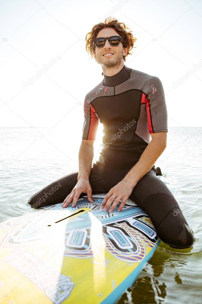 Surfer man in eyeglasses sitting on surf board in ocean — Stock Photo