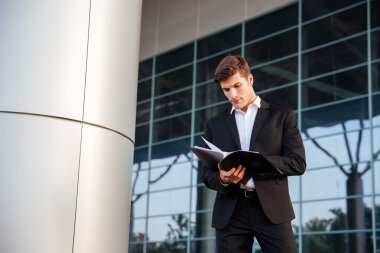 Açık havada ofiste ayakta iken belgeler üzerinden arıyor işadamı