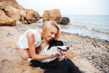 Köpeğini sarılma ve sahilde gülümseyen mutlu kadın