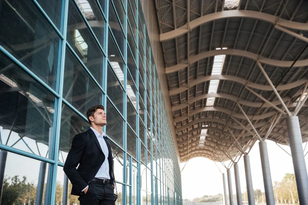 Впевнений красивий бізнесмен стоїть зі скляною будівлею на фоні — стокове фото
