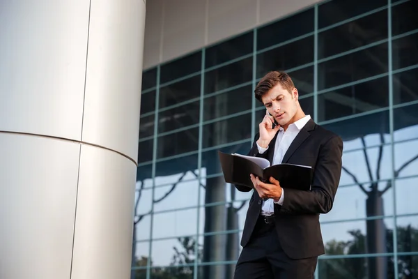 Businessman in suit holding folders and talking on the phone — Stock Photo, Image