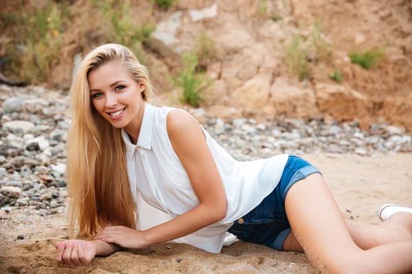 Feliz hermosa mujer joven acostada en la playa — Foto de Stock