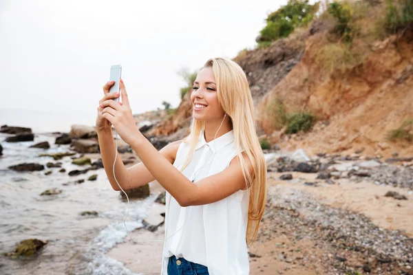 Woman taking selfie and listening to music from cell phone — Φωτογραφία Αρχείου