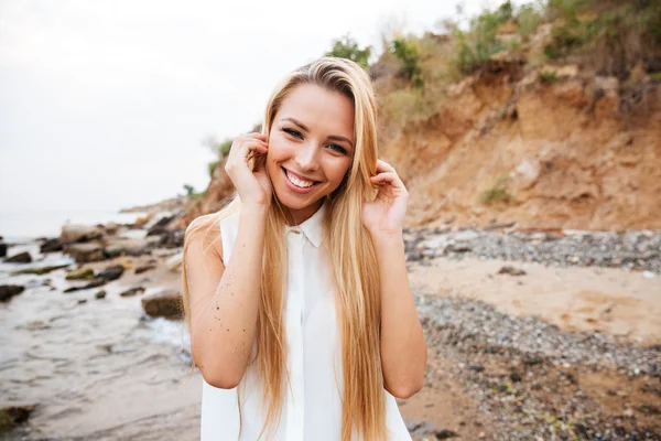 Glückliche attraktive junge Frau steht am Strand — Stockfoto