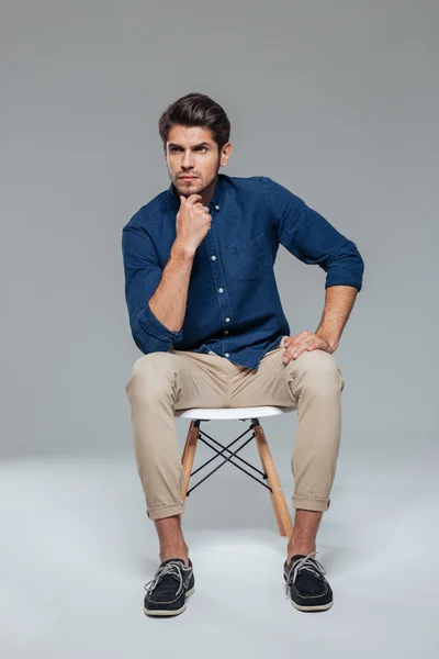 Pensive attraktiv casual ung man sittande på stol — Stockfoto