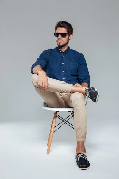 Snygg avslappnad man i suglasögon sitter på stolen — Stockfoto